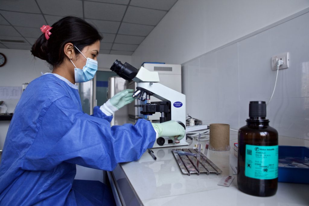 Researcher looks into microscope at a Salmonella bacteria.