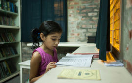 Nishita, out of school due to typhoid, reads a textbook at home. Photo credit: Suvra Kanti Das