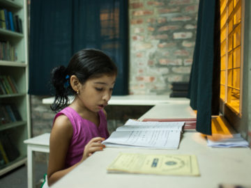 Nishita, out of school due to typhoid, reads a textbook at home. Photo credit: Suvra Kanti Das