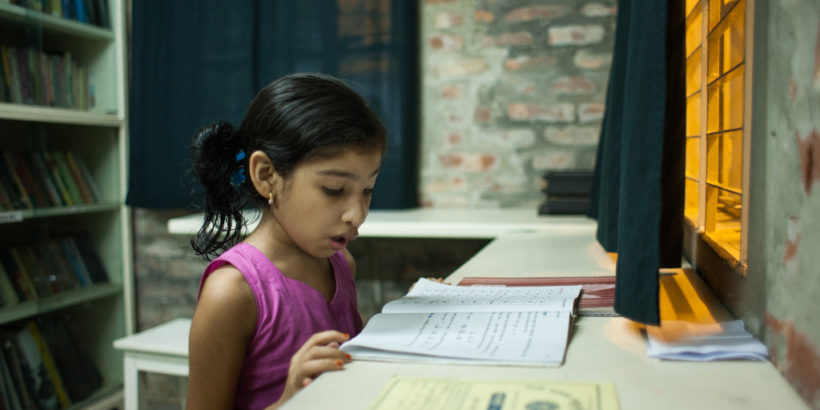 Nishita, out of school due to typhoid, reads a textbook at home. Photo credit: Suvra Kanti Das