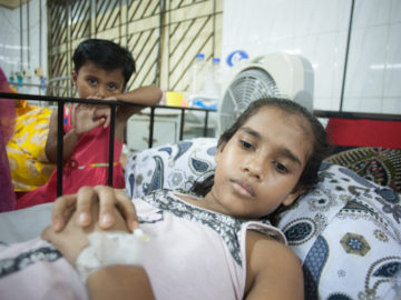 Nurunnahar had to miss school for two weeks with a case of typhoid that sent her to the hospital. One of her younger siblings is seen here watching over her hospital bed.