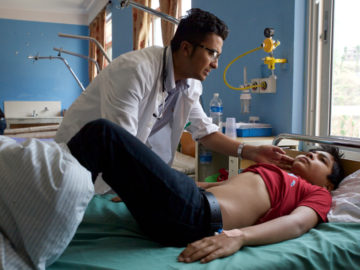 Dr. Asim Shrestha examines his patient, 13-year-old Subigyan Khanal, who has come into Dhulikhel Hospital complaining of fever, weakness and headache.