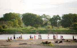 Villagers in Kenya gather at the bank of a river to gather water. When drought causes water sources to run dry, many resort to unsafe water sources.