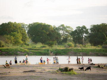 Villagers in Kenya gather at the bank of a river to gather water. When drought causes water sources to run dry, many resort to unsafe water sources.