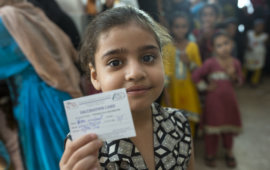 girl holds up immunization card