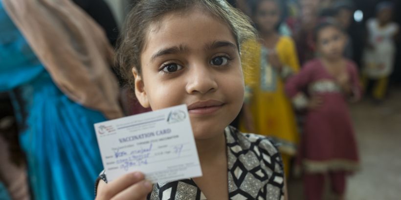 girl holds up immunization card