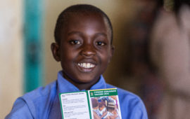 A young boy smiles with his vaccination card after receiving typhoid conjugate vaccine in Zimbabwe