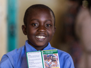 A young boy smiles with his vaccination card after receiving typhoid conjugate vaccine in Zimbabwe