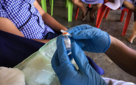 Health care worker's gloved hands hold TCV vial. Credit: Susan Nimarota Brown