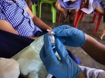 Health care worker's gloved hands hold TCV vial. Credit: Susan Nimarota Brown