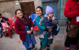 Two women smile while holding a baby