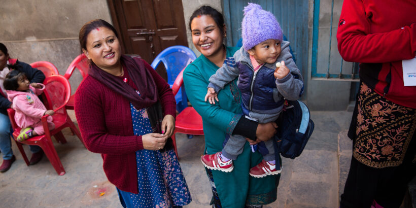 Two women smile while holding a baby