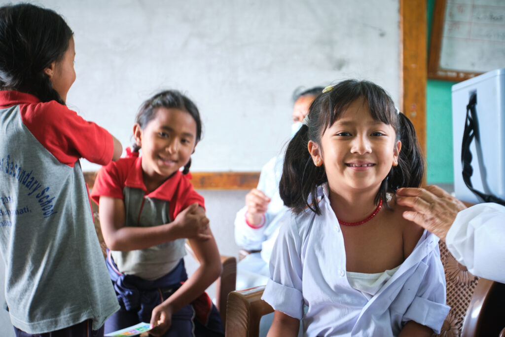 Two children smile after receiving TCV in Nepal.