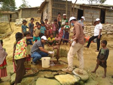 icddr,b team tests water supplies in Rohingya refugee camp, surrounded by crowd