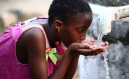 A young girl drinks from a makeshift handpump in Liberia. WASH and vaccines are complementary interventions that can work together to prevent waterborne diseases.