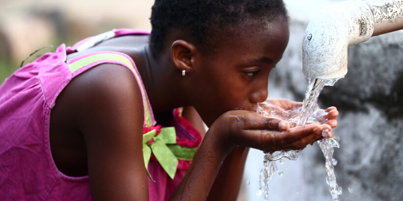 A young girl drinks from a makeshift handpump in Liberia. WASH and vaccines are complementary interventions that can work together to prevent waterborne diseases.