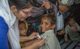 A smiling boy receives the typhoid conjugate vaccine during a 2018 vaccination campaign in Karachi, Pakistan.