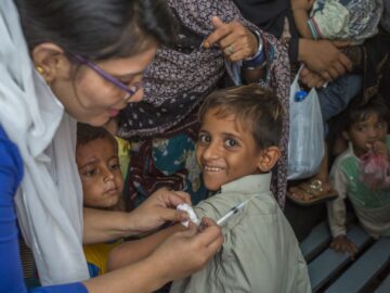 A smiling boy receives the typhoid conjugate vaccine during a 2018 vaccination campaign in Karachi, Pakistan.