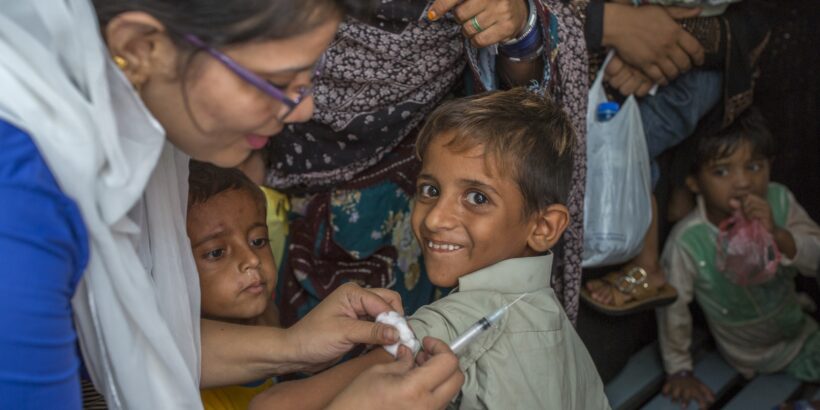 A smiling boy receives the typhoid conjugate vaccine during a 2018 vaccination campaign in Karachi, Pakistan.