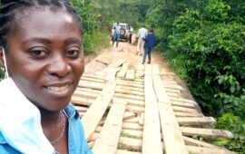 Patience Dapaah, a senior advocacy and communications advisor at PATH, stands with several team members as they inspect a wooden bridge in a forest in Liberia.