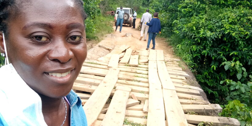 Patience Dapaah, a senior advocacy and communications advisor at PATH, stands with several team members as they inspect a wooden bridge in a forest in Liberia.