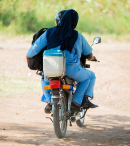 Health surveillance assistants from Chiseka Health Centre in Chikwawa, Malawi, ride a motorcycle to a community vaccination center. 