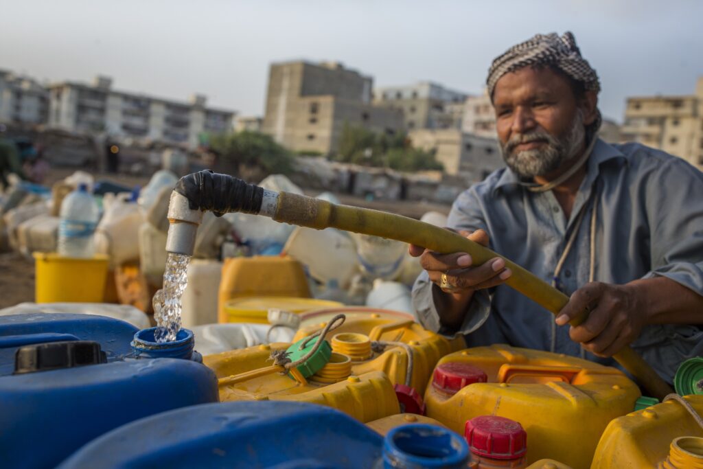 A man fills containers with water in Karachi, Pakistan. Climate change is intensifying the need to improve water infrastructure.