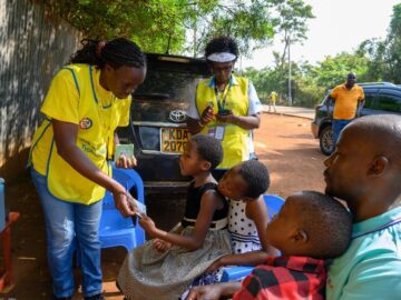 A vaccinator gives a TCV vaccination card to a child in Busia County, Kenya, during the country’s TCV introduction campaign in July 2025.