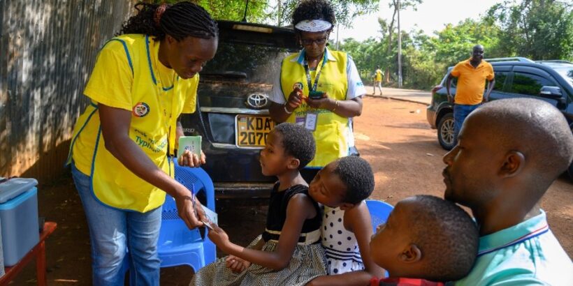 A vaccinator gives a TCV vaccination card to a child in Busia County, Kenya, during the country’s TCV introduction campaign in July 2025.